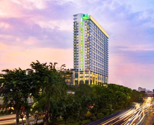 Holiday Inn & Suites Jakarta Gajah Mada, an IHG Hotel في جاكرتا: مبنى طويل عليه ضوء أخضر