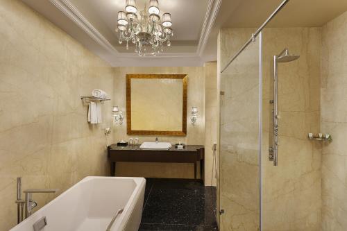 a bathroom with a tub and a sink and a mirror at La Marvella, Bengaluru in Bengaluru