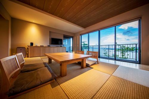 a living room with a table and a large window at Umino Ryotei Okinawa Nakamasou in Onna