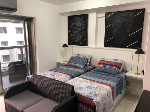 a bedroom with two beds and a couch and a window at PLAZA DE LA REPUBLICA CON GARAGE in Sao Paulo