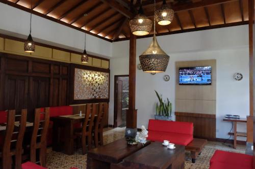 a dining room with a table and red chairs at Puri Langenarjan Guest House in Yogyakarta