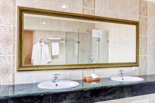a bathroom with two sinks and a large mirror at Shymkent Grand Hotel in Shymkent