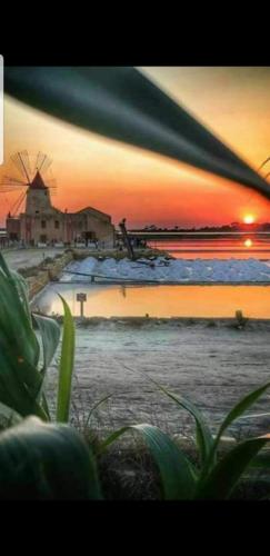 a sunset on a beach with a windmill in the background at La Culla di Adeodata in Marsala
