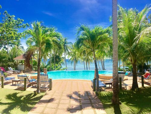un complejo con piscina y palmeras en Anda White Beach Resort en Anda