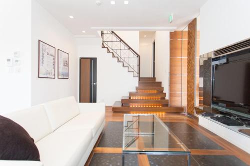 a living room with a white couch and a staircase at 暖炉之宿 コンセプトハウス星田 in Katano