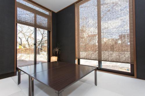 a dining room with a table and two large windows at 暖炉之宿 コンセプトハウス星田 in Katano