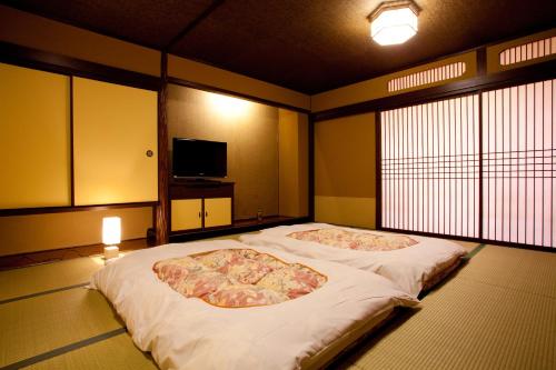 a bedroom with two beds in a room with a tv at Dantokan Kikunoya in Otsu