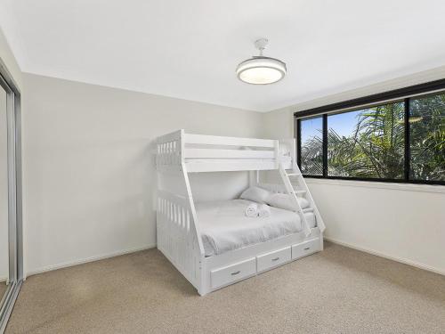 ein weißes Etagenbett in einem Zimmer mit Fenster in der Unterkunft North Entrance Beach House in The Entrance
