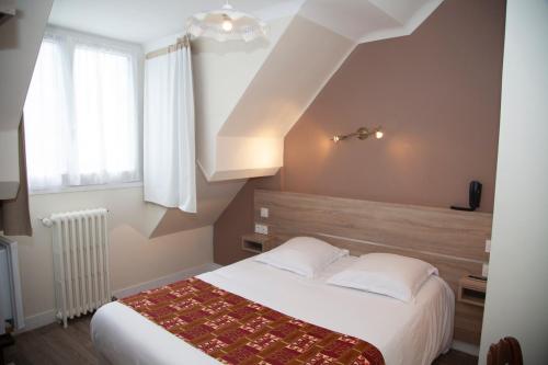 a bedroom with a white bed and a window at Hôtel La Pocatière in Coutances