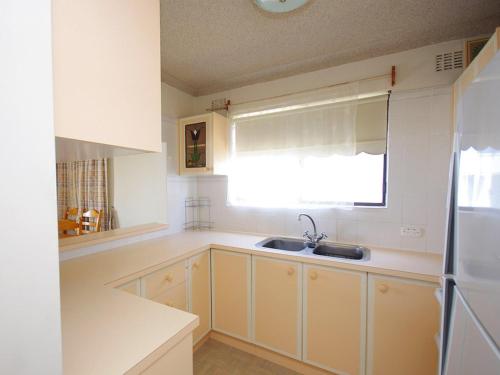 a kitchen with white cabinets and a sink and a window at Avilla Court 1 in The Entrance