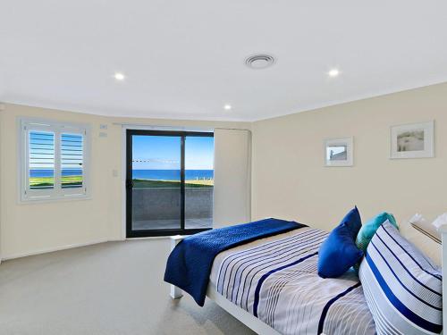 a bedroom with a bed and a large window at Beach Front Luxury in The Entrance