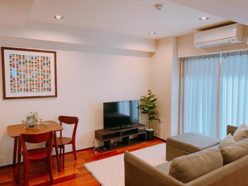 a living room with a couch and a table and a television at Dash Living Tsukiji in Tokyo