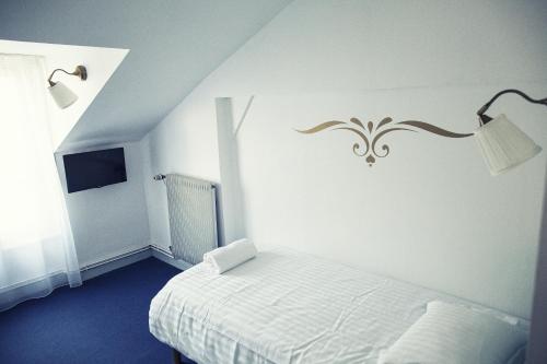 a white bedroom with a bed and a lamp at The Old Hotel Ravel Centre in Clermont-Ferrand