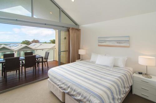 a bedroom with a bed and a balcony with a table at 16 Seine Bay Apartment in Augusta