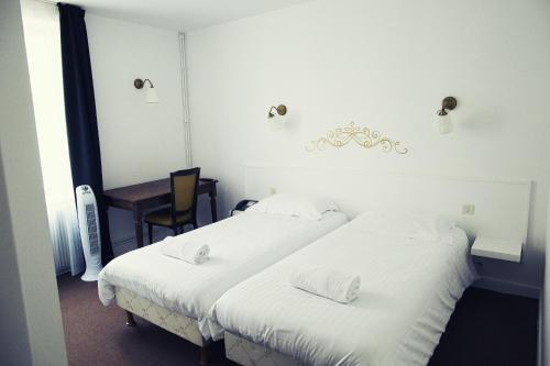 two beds in a room with a table and a chair at The Old Hotel Ravel Centre in Clermont-Ferrand