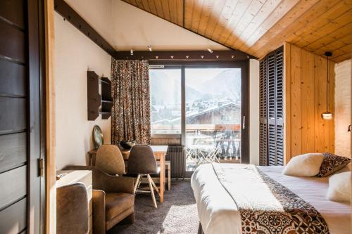 a hotel room with a bed and a desk and a window at Hôtel La Bergerie in Morzine