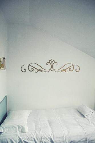 a bedroom with a white bed and a white wall at The Old Hotel Ravel Centre in Clermont-Ferrand