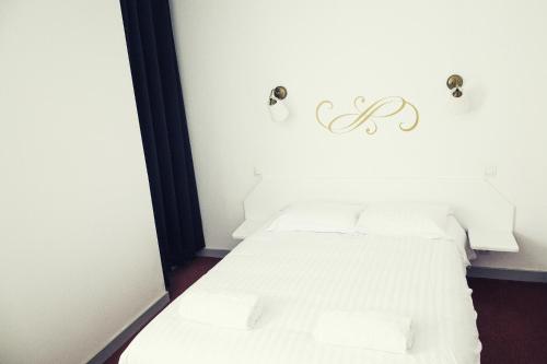 a bedroom with a white bed with two pillows at The Old Hotel Ravel Centre in Clermont-Ferrand