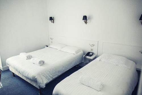 two beds in a room with white walls at The Old Hotel Ravel Centre in Clermont-Ferrand