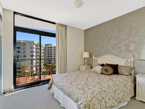 a bedroom with a large bed and a balcony at Crystal Views 24 in The Entrance