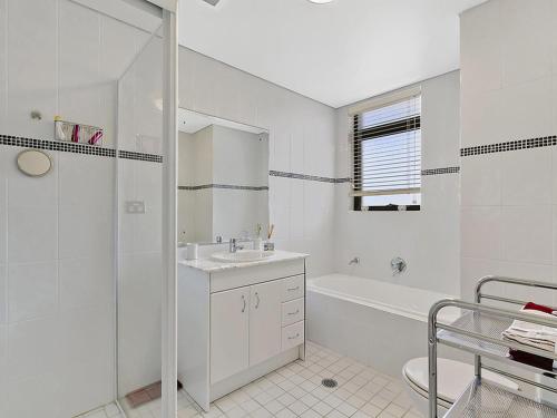 a white bathroom with a sink and a shower at Crystal Views 24 in The Entrance