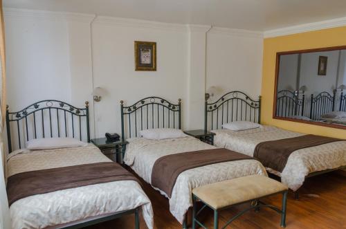 a room with three beds and a mirror at Hotel El Altar in Riobamba