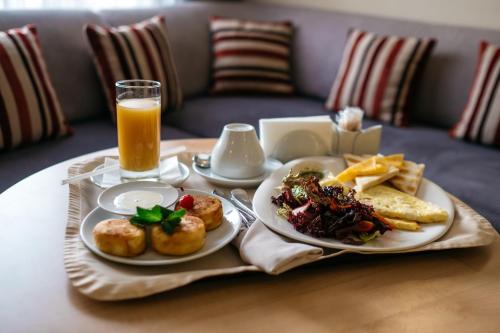 une table avec deux assiettes de nourriture et un verre de jus d'orange dans l'établissement Grand Avenue by USTA Hotels, à Iekaterinbourg