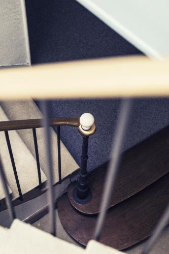 a spiral staircase with a metal railing with a knob at The Old Hotel Ravel Centre in Clermont-Ferrand