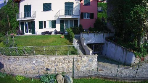 a house with a stone wall and a fence at Orchidea Apartment in Bellagio