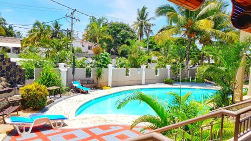 a swimming pool in a yard with palm trees at Abrico Apartment in Trou aux Biches