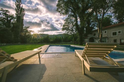 a swimming pool with two wooden chairs next to a house at Stara kuća Estate in Ljubuški