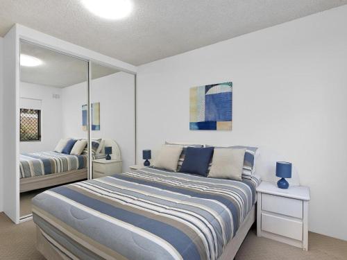 ein Schlafzimmer mit einem großen Bett und einem Spiegel in der Unterkunft Dolphin Court 5 in The Entrance