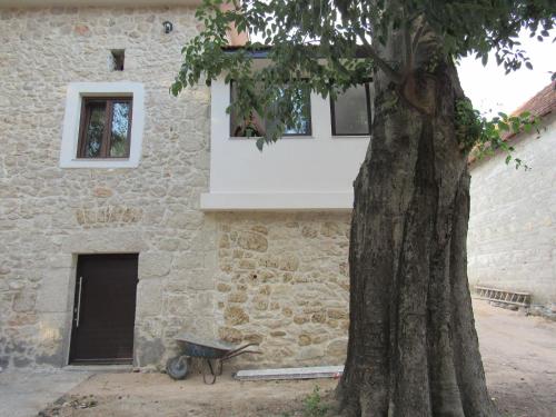 a stone building with a wheelbarrow next to a tree at Stara kuća Estate in Ljubuški