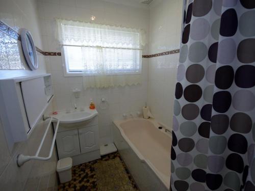 uma casa de banho branca com uma banheira e um lavatório e uma banheira em Fravent house em Toukley