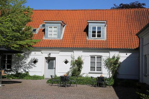a white house with an orange roof and tables and chairs at Tune Kursuscenter in Greve