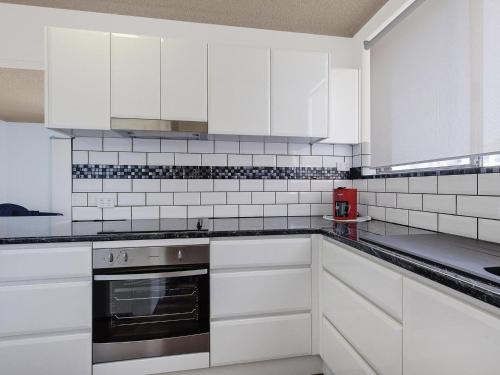 a white kitchen with white cabinets and appliances at Granada in The Entrance