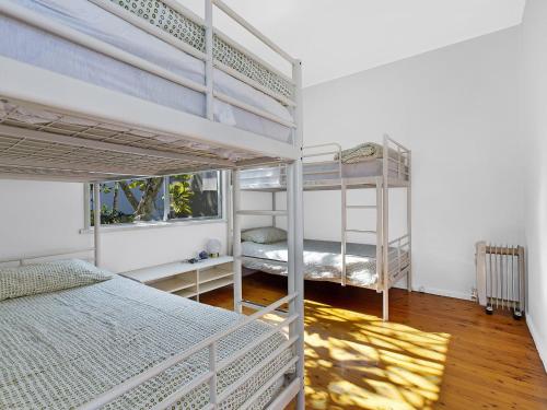 a bedroom with two bunk beds and a window at Lake Edge Cottage in Budgewoi