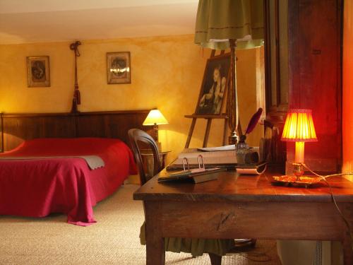 ein Schlafzimmer mit einem Bett und einem Schreibtisch mit einer Lampe in der Unterkunft Domaine du Peyron in Quintenas