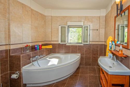 uma casa de banho com uma banheira e um lavatório em LOURDAS BEACH VIEW VILLA em Kefalonia