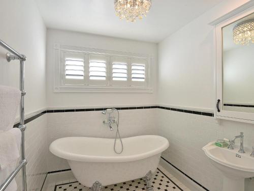Baño blanco con bañera y lavamanos en Margaret's Hamptons Beach House en Hawks Nest