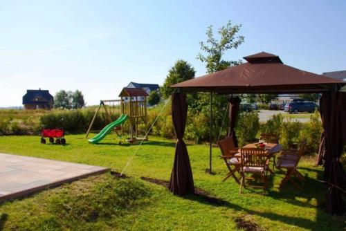 a backyard with a table and an umbrella and a swing at Ferienhaus Tobias in Ostseebad Karlshagen