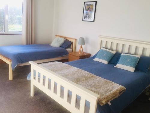 a bedroom with two beds with blue sheets at Cosy Apartment in Miltown Malbay