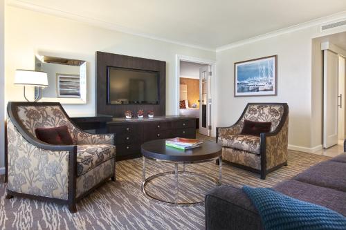 a living room with a couch and chairs and a television at Fairmont Waterfront in Vancouver