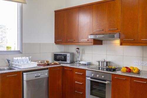 a kitchen with wooden cabinets and stainless steel appliances at Faros BeachFront Villa in Pervolia