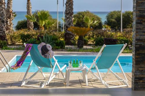 two chairs and a table next to a pool at Faros BeachFront Villa in Pervolia