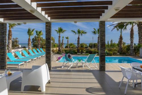 a woman sitting in chairs by a swimming pool at Faros BeachFront Villa in Pervolia