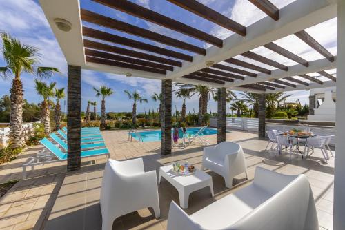 a patio with white furniture and a swimming pool at Faros BeachFront Villa in Perivolia