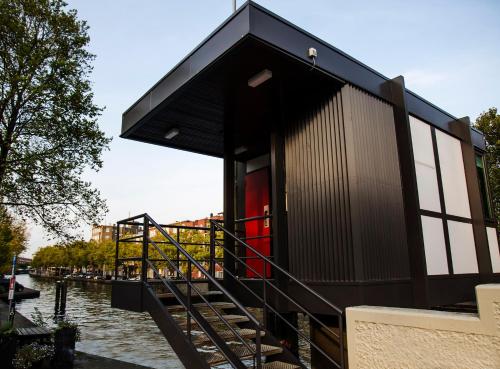 a house on a river with a black roof at SWEETS - Theophile de Bockbrug in Amsterdam