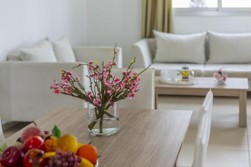 a vase of flowers on a table with fruit on it at Faros BeachFront Villa in Pervolia