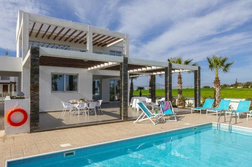 a villa with a swimming pool and a house at Faros BeachFront Villa in Pervolia